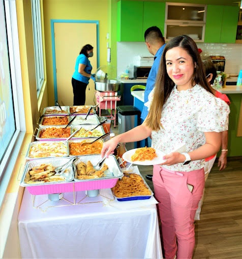 A lady holding a white plate with spaghetti and taking food from the food station at BirthdayLand